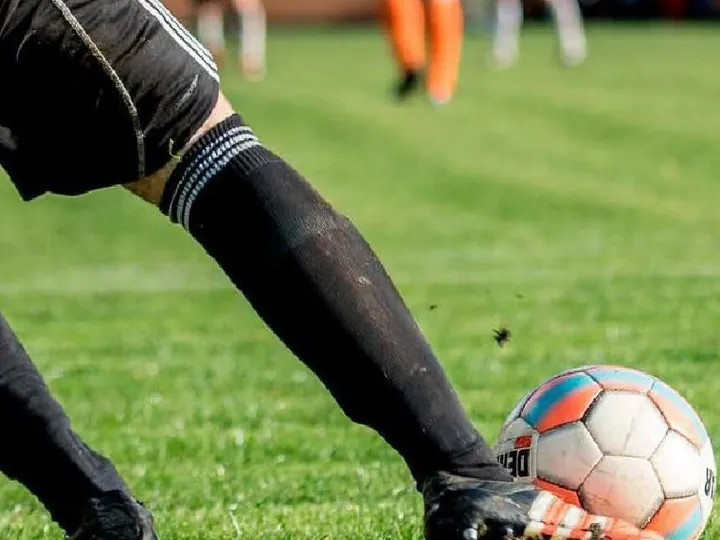 Jugador de fútbol a punto de patear el balón en una cancha de césped
